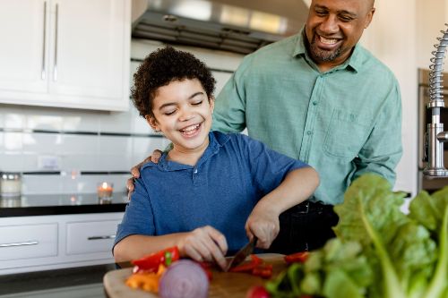 african american man and boy cooking together in kitchen