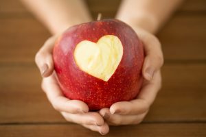 hands holding apple with a heart cut out of the center