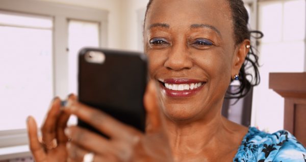 woman smiling while holding smartphone