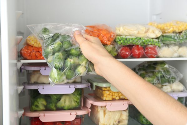 Woman Putting Plastic Bag With Brussels Sprouts In Freezer
