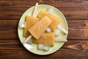 peach popsicles on a plate with wooden surface in background