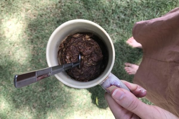 hand holding mug with chocolate zucchini cake outside