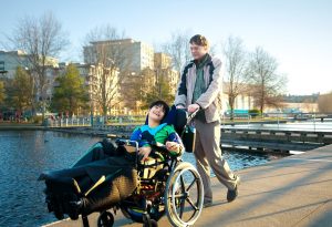 father pushing disabled son in wheelchair over a bridge 