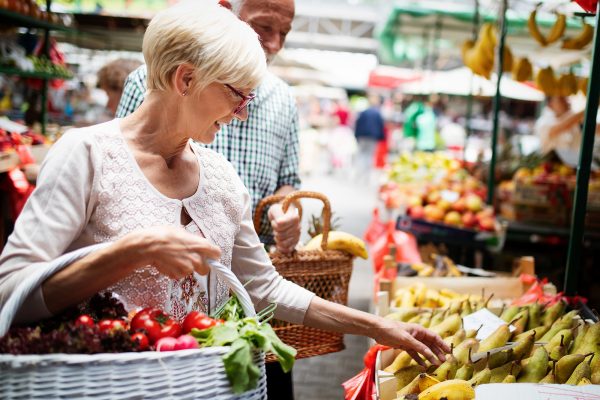 elderly woman buying vegetables at an outdoor market