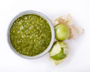 tomatillo sauce in a bowl on a white surface 