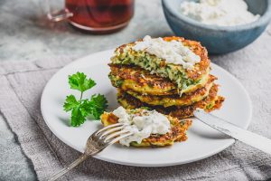 Zucchini pancakes topped with parsley on a white plate 