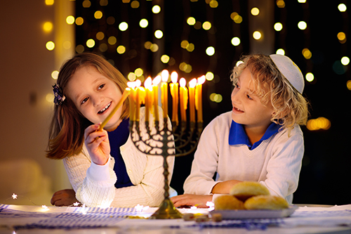 Children lighting candles on traditional menorah.