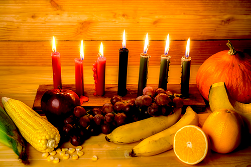 Kwanzaa holiday concept with decorate seven candles red black and green gift box pumpkin, corn and fruit on wooden desk and background.