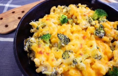 black skillet containing cheesy macaroni and cheese with broccoli pieces