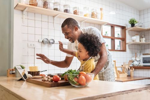 father and son cooking together while video chatting