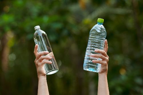 two hands raising water bottles in the air 