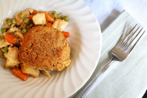 Chicken pot pie with drop biscuit topping on a white plate next to fork