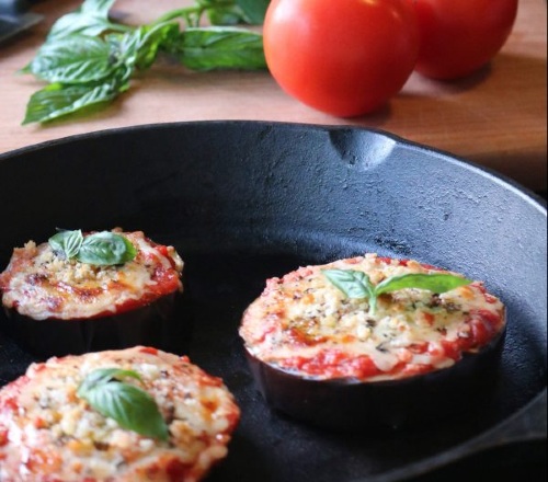 Photo shows three eggplant "pizzas" in a cast iron skillet