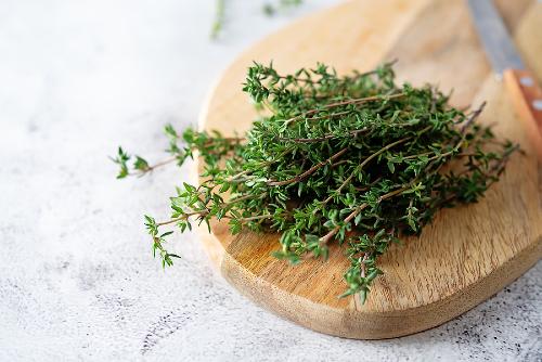 fresh thyme leaves lying on a wooden cutting board 