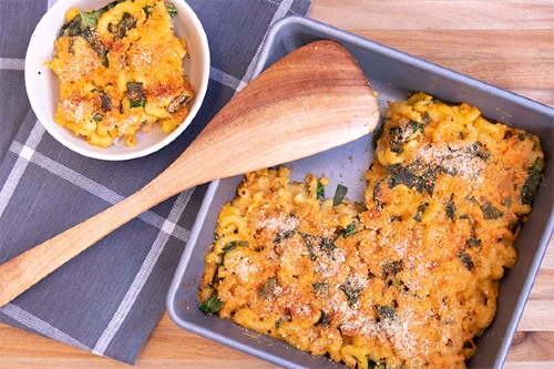 Mac and cheese square scooped out of square pan and into a white bowl