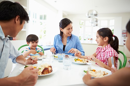 Family Sitting At Table Eating and laughingMeal Together