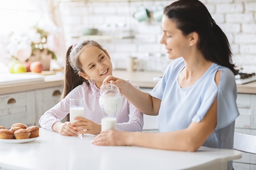 Mother and daughter drinking milk in kitchen together.