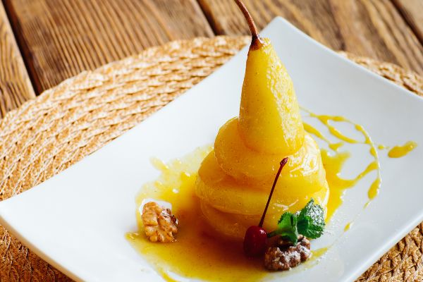 Pear on white plate with orange sauce