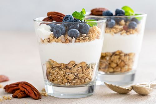 two yogurt parfaits with pecans and blueberries on top