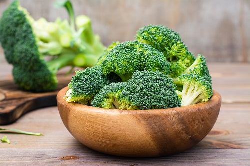 Wooden bowl of raw and cut broccoli florets