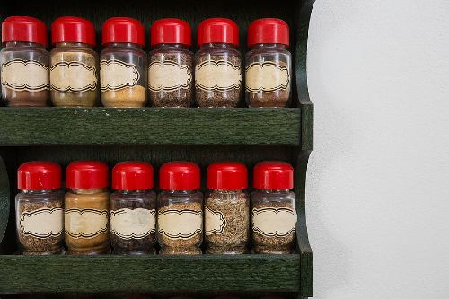 jars of herbs and spices on a wooden, two-tiered rack