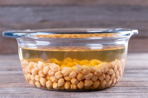 Dried chickpea beans soaking in a glass bowl of water