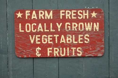 Maroon wooden sign reading "Farm Fresh Locally Grown Vegetables & Fruits"