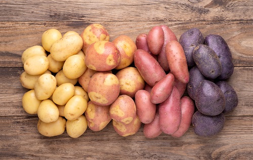 yellow, red, and purple starchy potatoes on a wooden table