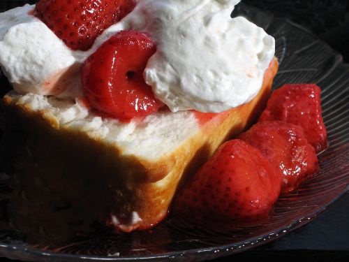  angelfood cake topped with strawberries and whipped cream on a black plate