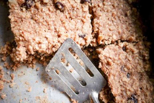 metal spatula serving baked granola bars from a metal pan