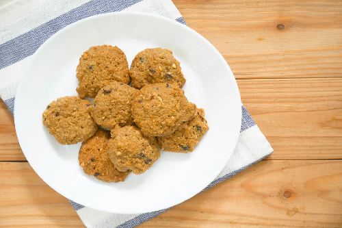 banana oatmeal raisin cookies on a white plate sitting on a wooden countertop