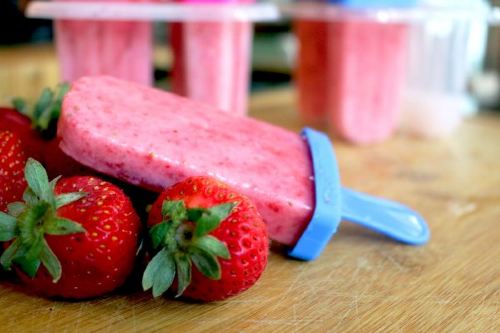 strawberry popsicle sitting on a bed of fresh strawberries