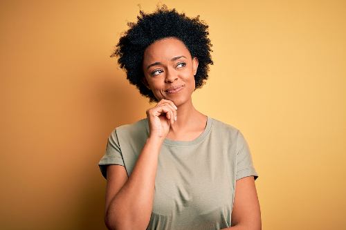 african american woman thinking intently in front of a light brown background 