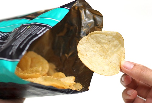 Hand holding potato chip out of snack bag