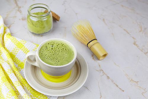 cup of matcha with a jar of matcha powder sitting to the side 