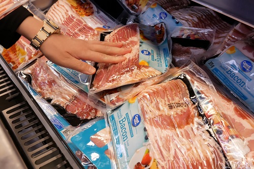 Woman looking at packaged bacon in a store