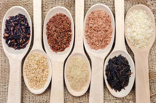 Assortment of different colored rice on wooden spoons