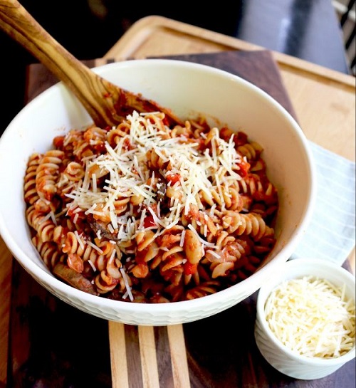 bowl of red sauce rotini pasta sprinkled with parmesan cheese