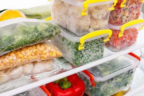 freezer meals packaged in plastic bags and tupperware sitting on a shelf in a freezer 