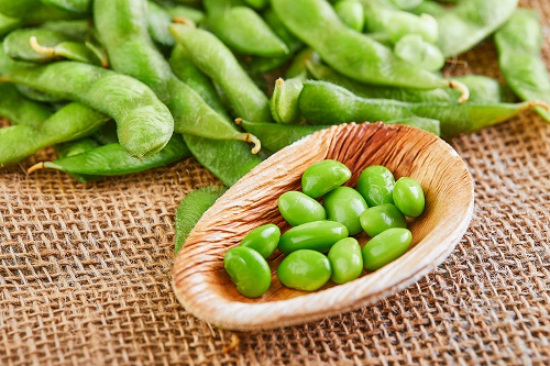 Edamame or soybeans in a wooden plate on a brown sackcloth.