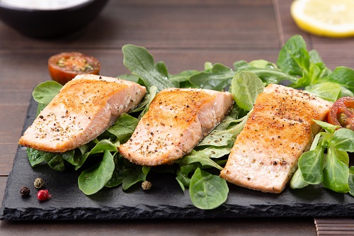 Salmon fillets on slate dish on wooden table background.