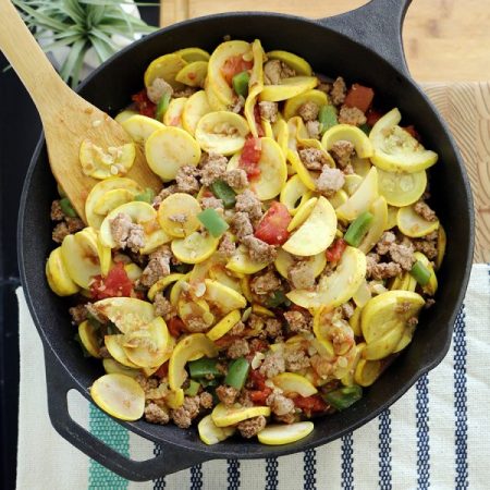 yellow squash, turkey, and vegetable stir fry sits in a black cast iron skillet