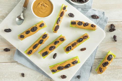 homemade "bugs on a log" placed on a white plate 