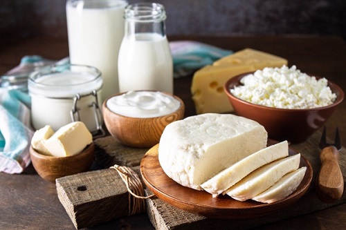 Set of different dairy products (milk, sour cream, cottage cheese, yogurt and butter) on a rustic wooden countertop.