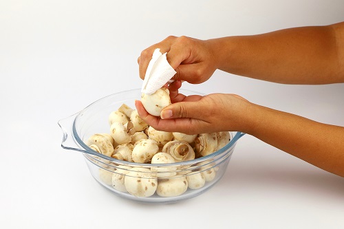 Close-up shot of the hands of a female chef cleaning mushrooms prior to chopping