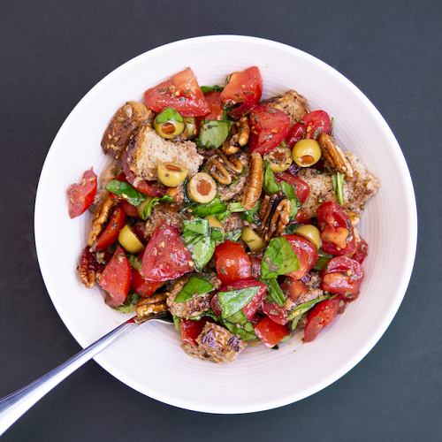 bread salad with olives, tomato, basil, in a white bowl