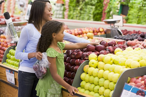 Woman and daughter shopping for apples at a grocery store