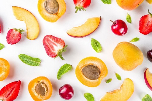 Summer background with fresh fruits and berries on white background. Set of various seasonal fruit and berry - strawberry, apricots, peach slices, cherry, mint.