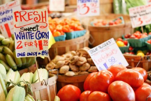 Bins of fresh fruits and vegetables with signs and prices