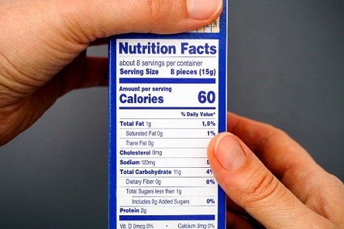 Hands hold the side of a blue food box with the nutrition facts label